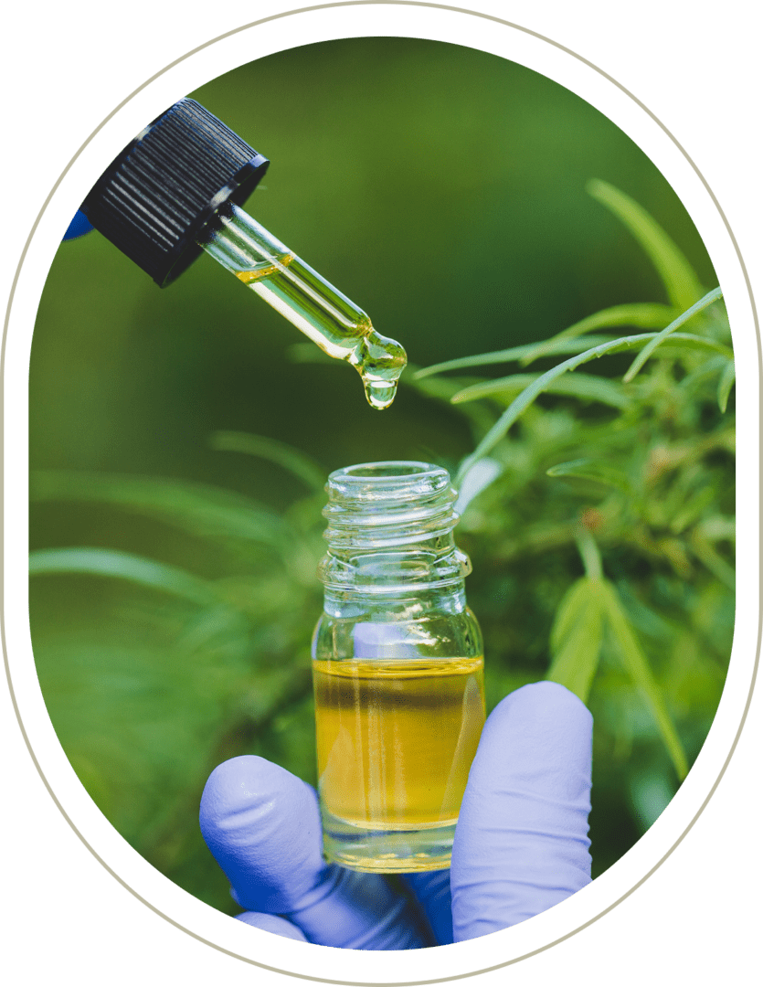 A gloved hand holds a small dropper bottle filled with yellow liquid, against a backdrop of green plants. A drop is suspended from the dropper above the bottle.